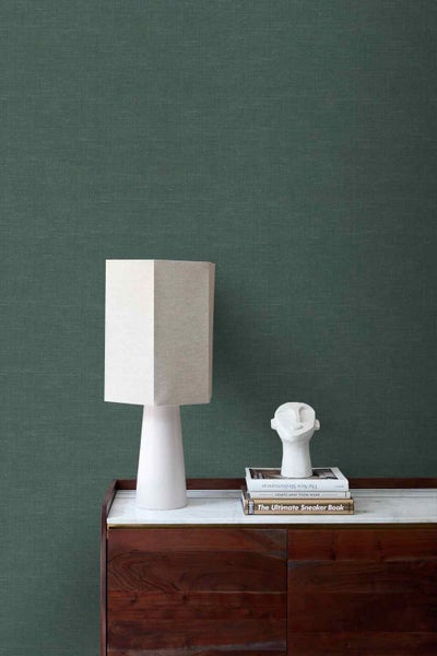 Strukturierte Tapete in Leinenoptik an einer Wand in einem modern eingerichteten Raum mit Holzsideboard und Lampe.