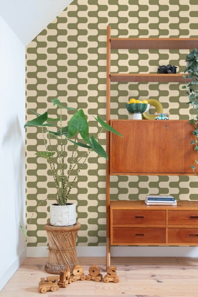 Vliestapete mit geometrischem Muster in einem hellen Raum mit Holzregal, Zimmerpflanze und Parkettboden.
