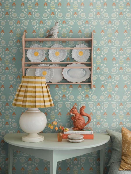 Dekoratives Interieur mit Geschirrregal, floral gemusterter Tapete und Tischlampe