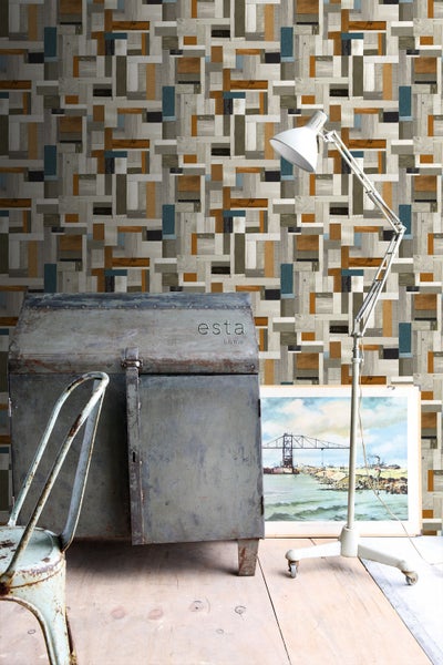 Raumszene mit geometrischer Holzoptik-Tapete, antikem Metallschrank, Stehlampe und Vintage-Dekoration