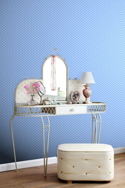 Frisiertisch mit Spiegel, Lampe und Hocker vor einer gepunkteten Tapete