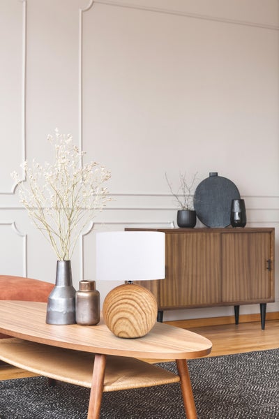 Wohnzimmer mit Holzmöbeln, Tischleuchte und Dekoration