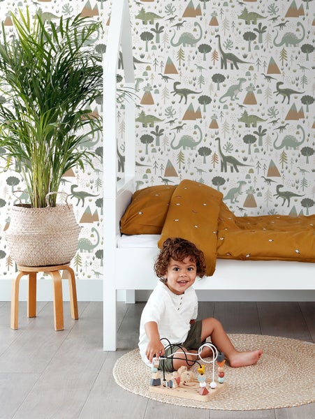 Kinderzimmer mit weißem Himmelbett, Dinosaurier-Tapete, Zimmerpflanze und spielendem Kind