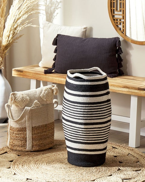 Dekorative Szene mit geflochtenem Korb, gestreifter Vase und Kissen auf einer Bank