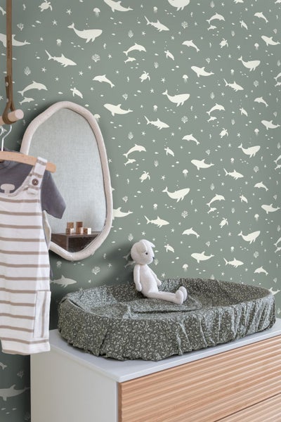 Ein Kinderzimmer mit einem Wickeltisch, einem Spiegel und einer Tapete mit Meeresmotiven