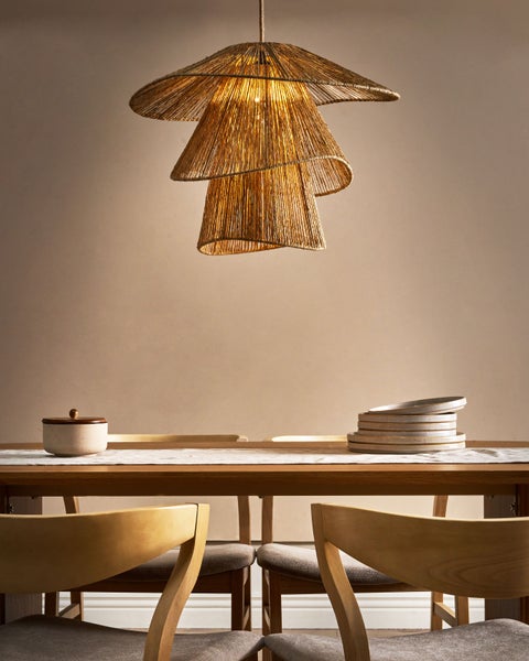 Esszimmer mit Tisch, Stühlen, Geschirr und einer Hängelampe aus Naturmaterialien.