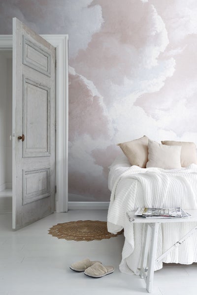 Helles Schlafzimmer mit Wandbild, Bett, Beistelltisch, Teppich und geöffneter Tür