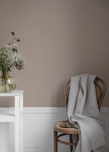 Dekoratives Zimmer mit Blumenstrauß, weißem Tisch und Stuhl mit Decke.