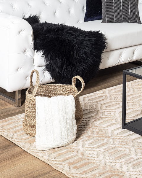 Szene mit Sofa, Korb, Kissen und Teppich für ein gemütliches Wohnambiente.