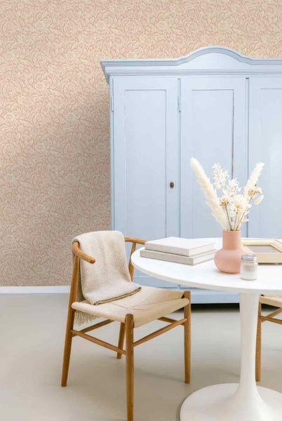 Hell eingerichteter Raum mit floral gemusterter Tapete, einem hellblauen Schrank, einem Holzstuhl und einem runden weißen Tisch.