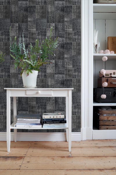 Szene mit grauer Tapete im Patchwork-Design, weißem Tisch, Pflanze und Regal