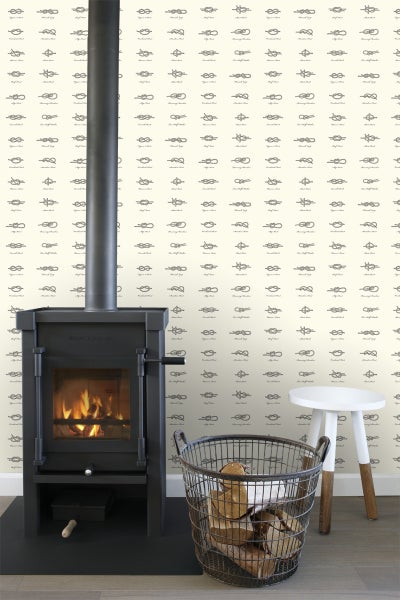 Raum mit Kaminofen, Holzkorb und Tapete mit Knotenmotiven