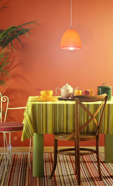 Helle, freundliche Esszene mit Tisch, Stühlen, Geschirr und Pendelleuchte