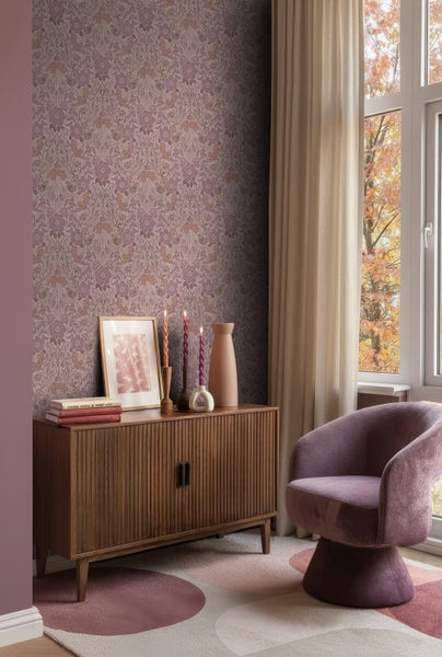 Wohnzimmer mit floraler Tapete, Holzkommode und Sessel