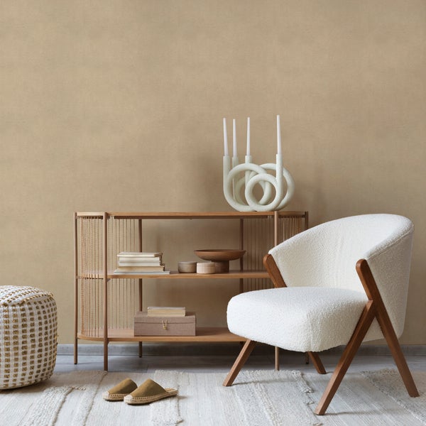 Modernes Wohnzimmer mit hellbrauner Strukturtapete, einem weißen Sessel mit Holzgestell und einem Holzregal mit Dekoartikeln auf einem Teppich.