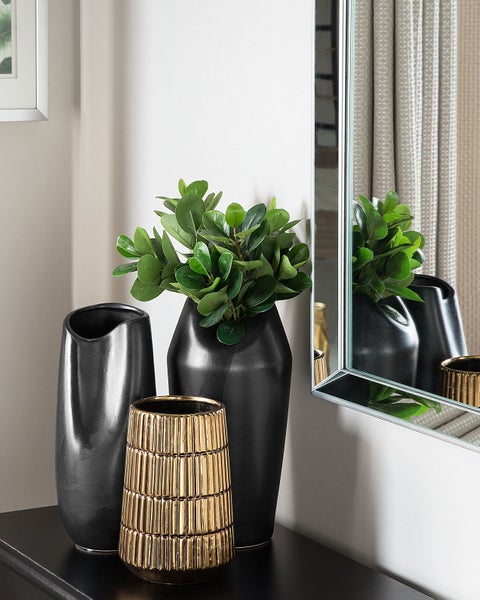 Dekorative Anordnung mit schwarzen Vasen und einer goldenen Vase auf einem Tisch mit Spiegel