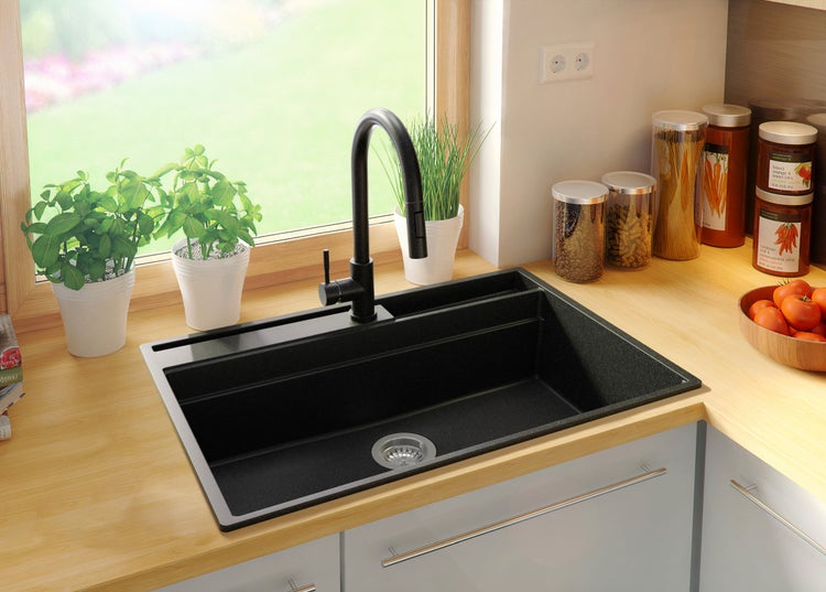 Schwarzes Spülbecken mit Wasserhahn in einer hellen Küche