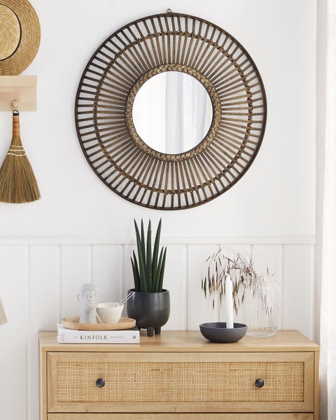Dekoratives Interieur mit rundem Spiegel, Kommode und Pflanzen
