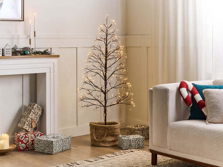 Dekoratives Wohnzimmer mit beleuchtetem Deko-Baum, Geschenken und Sofa.