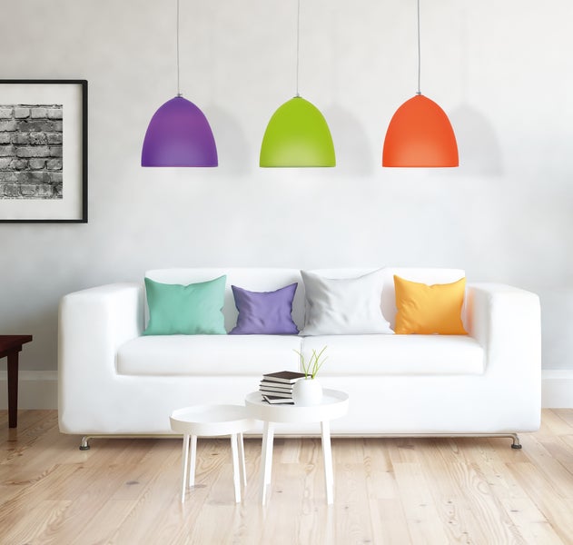 Helles Wohnzimmer mit weissem Sofa, bunten Kissen und Lampen