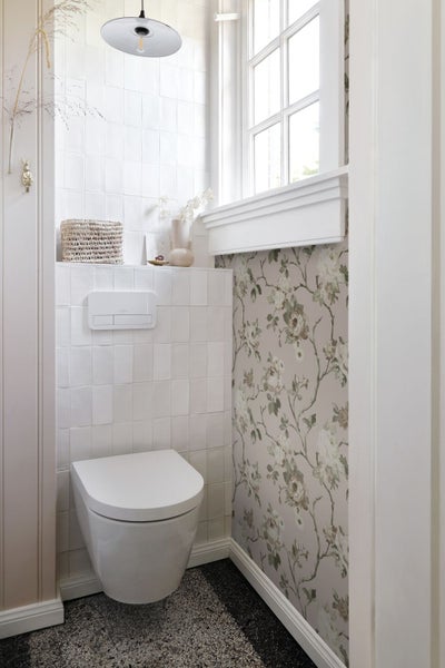 Helles Badezimmer mit Toilette, Spülkasten, Fliesen, Tapete und Fenster