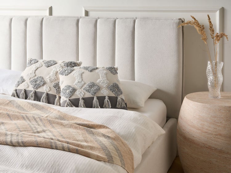 Elegantes Schlafzimmer mit Polsterbett, Zierkissen und Nachttisch