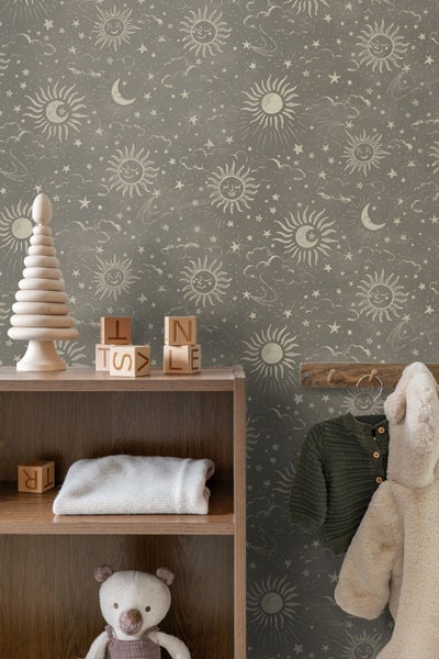 Kindertapete mit Motiven von Sonnen, Monden und Sternen in einem Kinderzimmer mit Holzregal und Kinderkleidung.