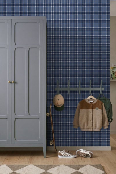 Modernes Kinderzimmer mit blau-weiß karierter Vliestapete, grauem Kleiderschrank, Garderobe, Skateboard und hellem Holzboden.