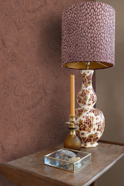 Dekorative Szene mit gemusterter Tapete, floraler Tischleuchte, Kerze und dekorativer Schale auf einem Tisch