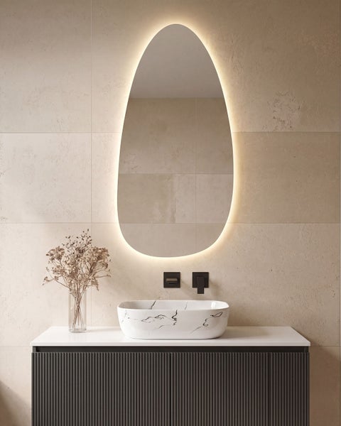 Modernes Badezimmer mit hinterleuchtetem organisch geformtem Spiegel, Marmor-Optik Aufsatzwaschbecken und geriffeltem Waschtischunterschrank.