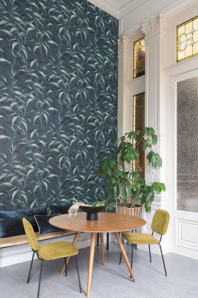 Wohnraum mit gemusterter Tapete, Esstisch, Stühlen und Zimmerpflanze