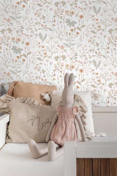 Tapete mit Blumenmuster, Kissen und Stoffhase auf einer Bank