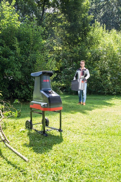 AL-KO Walzenhäcksler Easy Crush LH 2810 auf einer Rasenfläche im Garten, im Hintergrund ein Mann mit der dazugehörigen Fangbox.