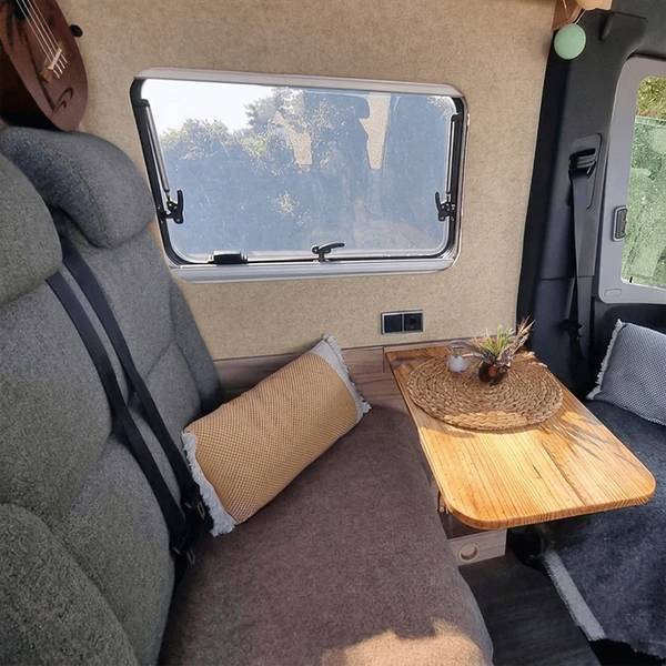 Innenraum eines Wohnmobils mit Sitzgelegenheiten, Tisch und Fenster