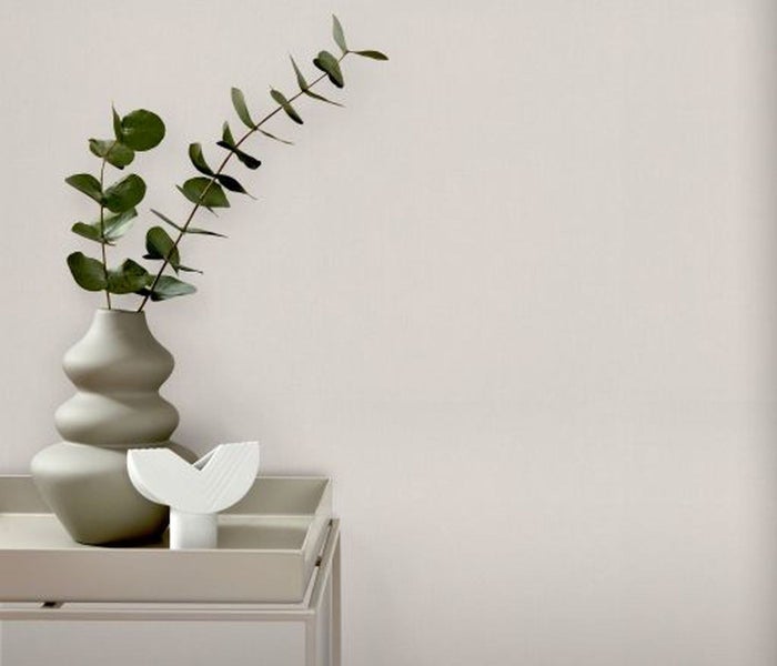 Dekorationselemente wie eine Vase mit Eukalyptus auf einem Tisch vor einer Wand