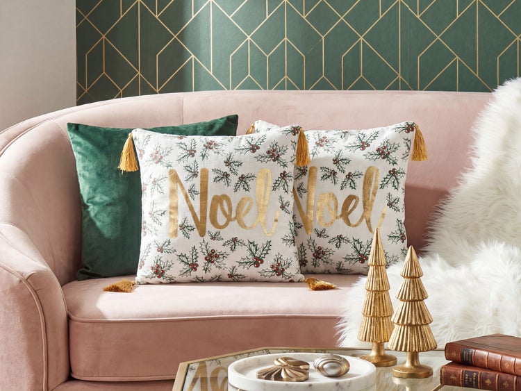 Dekokissen Noel mit Stechpalmenmuster und Quasten auf einem Sofa, kombiniert mit Samtkissen und weihnachtlicher Dekoration.