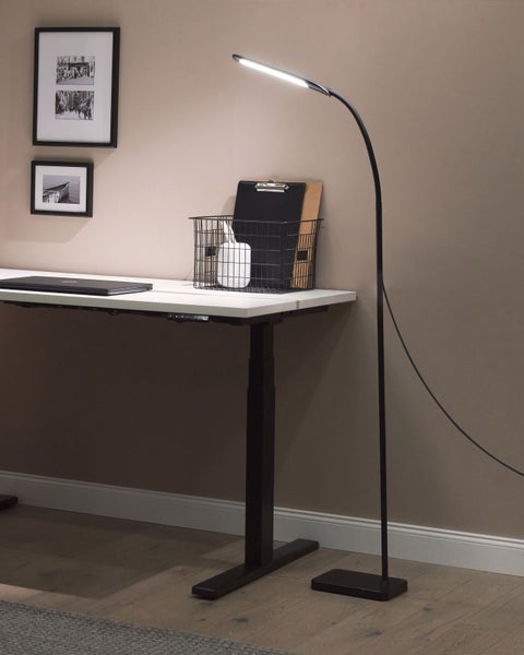 Stehleuchte neben einem höhenverstellbaren Schreibtisch mit Schreibtischutensilien