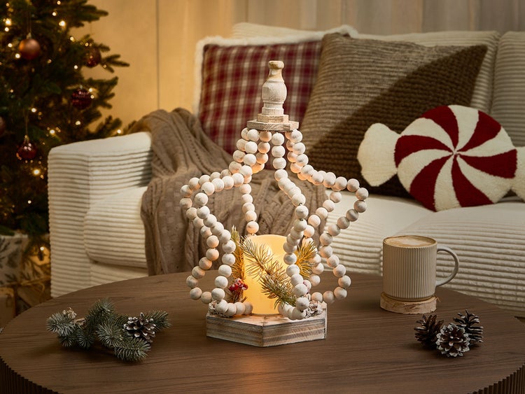 Dekoratives Arrangement mit Sternleuchte, Tasse Kaffee und Weihnachtselementen auf einem Tisch