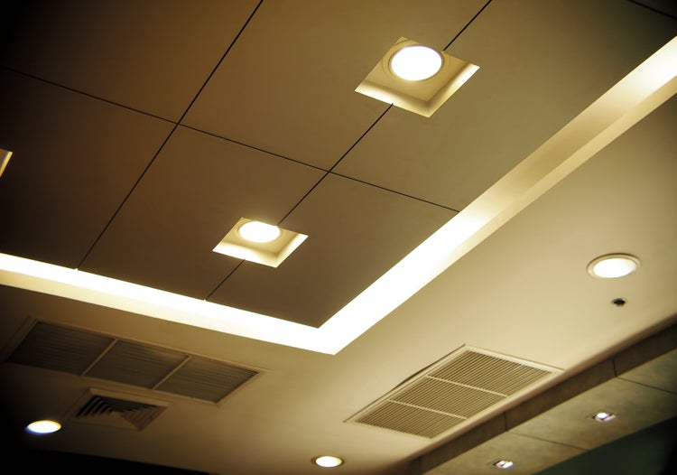 Decke mit quadratischen Paneelen, eingebauten Leuchten und Lüftungsgittern