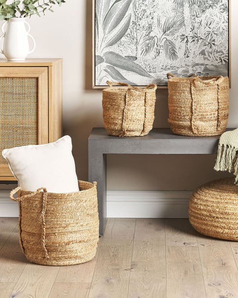 Geflochtene Körbe aus Jute in verschiedenen Größen und ein passender Sitzpouf in einem hell eingerichteten Raum mit Holzkommode.