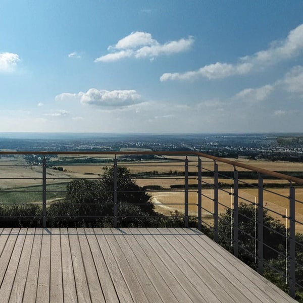 Modernes Balkongeländer mit Holzhandlauf und Edelstahlseilen auf einer Holzterrasse mit weitem Ausblick über eine Landschaft.