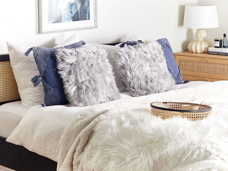 Dekoratives Schlafzimmer mit Kissen und Überwurf aus Kunstfell