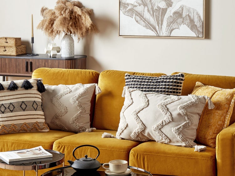 Dekoratives Wohnzimmer mit gelbem Sofa und Zierkissen auf einem Couchtisch