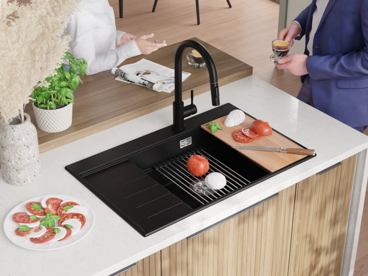 Küchenszene mit schwarzer Spüle, Armatur, Schneidebrett und Zutaten für Caprese.