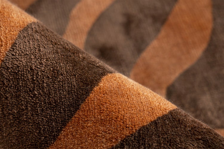 Nahaufnahme eines weichen Kurzflor-Teppichs mit wellenförmigem Streifenmuster.