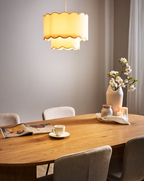 Esstischszene mit Stoff-Hängeleuchte, Dekoration und Stühlen