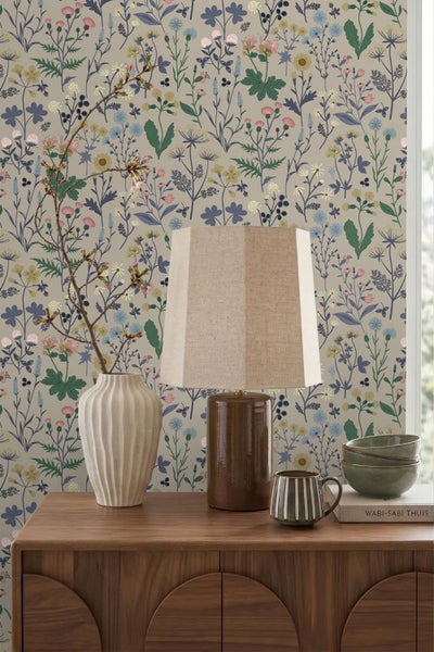 Wohnszene mit floraler Vliestapete, Wiesenblumenmuster, Holz-Sideboard, Keramiklampe und Vase, im natürlichen und organisierten Stil.