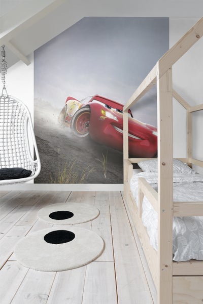 Kinderzimmer mit Wandbild von Lightning McQueen, Hängekorbsessel und Holzbett