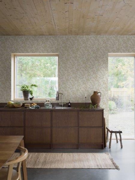 Helles Schlafzimmer mit floraler Tapete, Bett und geöffneter Holztür.