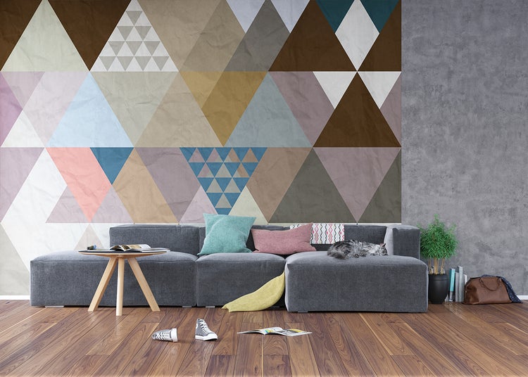 Wohnzimmer mit geometrischer Tapete, grauer Couch und Holzboden